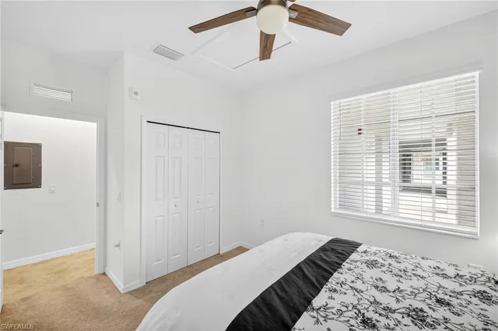Bedroom with light colored carpet, electric panel, a closet, and ceiling fan