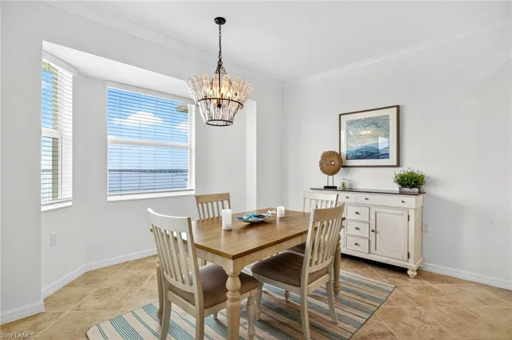 Dining area featuring crown molding, a chandelier, and light tile patterned floors