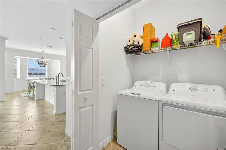 Laundry room with light tile patterned floors, separate washer and dryer, and a chandelier