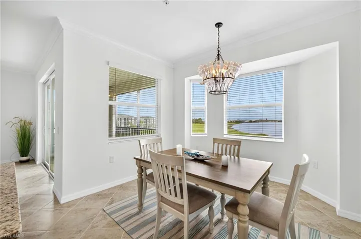 Dining space with crown molding, light tile patterned floors, and a chandelier