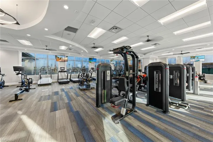 Exercise room with carpet floors, a ceiling fan, recessed lighting, and a drop ceiling