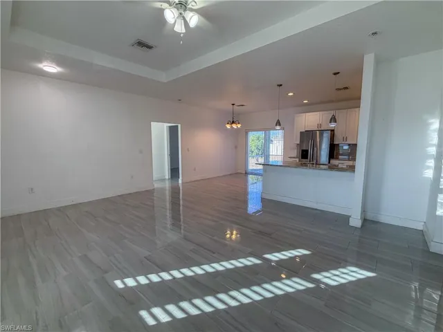 Unfurnished living room with a chandelier, a ceiling fan, and dark wood-style floors