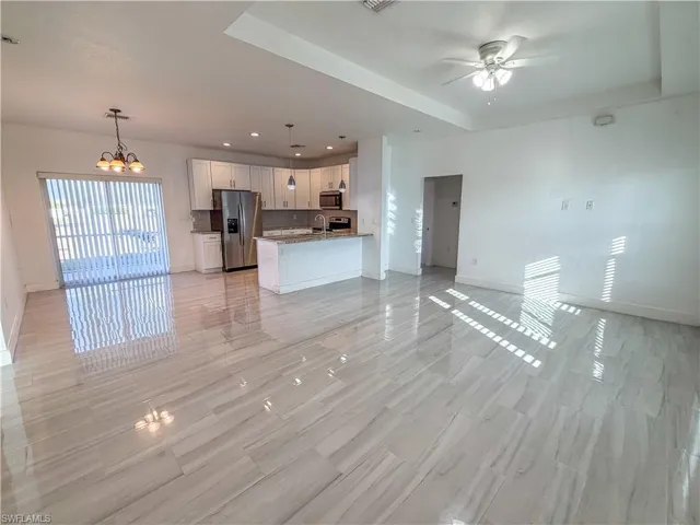 Unfurnished living room with a chandelier, wood finish floors, and ceiling fan