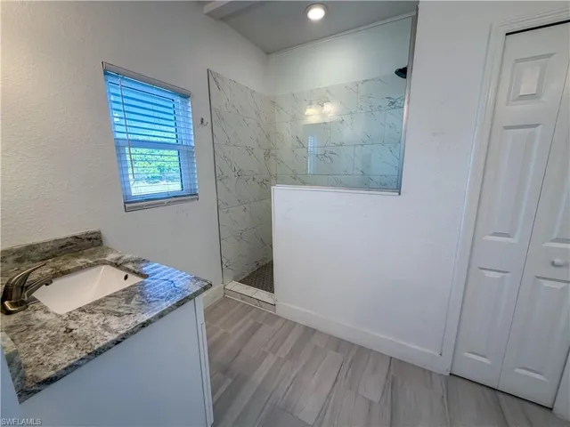 Bathroom featuring vanity, a walk in shower, and a textured wall