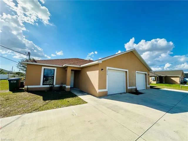 Single story home featuring stucco siding, a garage, driveway, and a front lawn