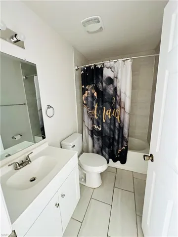 Bathroom with vanity, shower / tub combo with curtain, and light tile patterned flooring