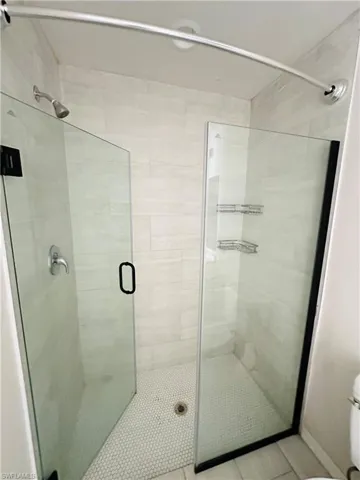 Full bath featuring a shower stall and light tile patterned flooring