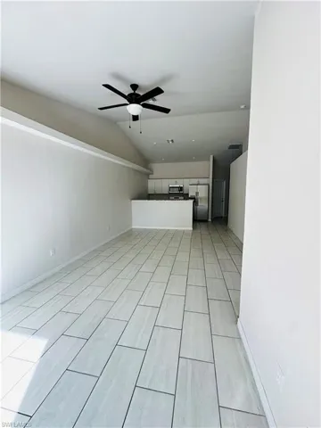 Unfurnished living room featuring vaulted ceiling, ceiling fan, and wood finish floors