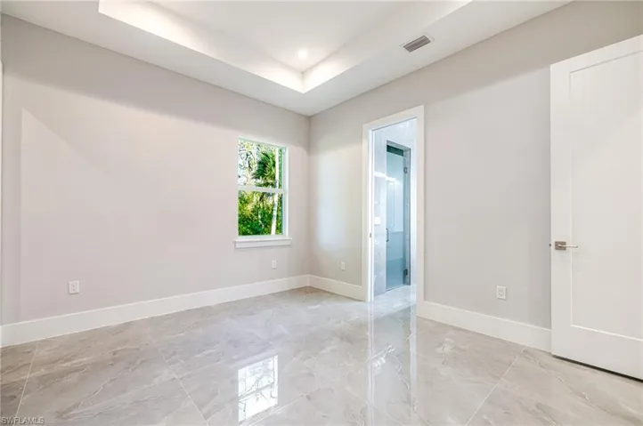 Empty room featuring a tray ceiling and baseboards