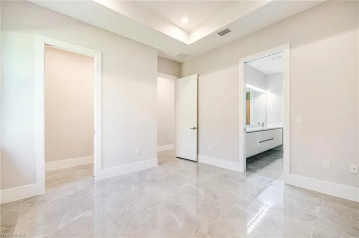 Unfurnished bedroom with connected bathroom, recessed lighting, and light marble finish flooring