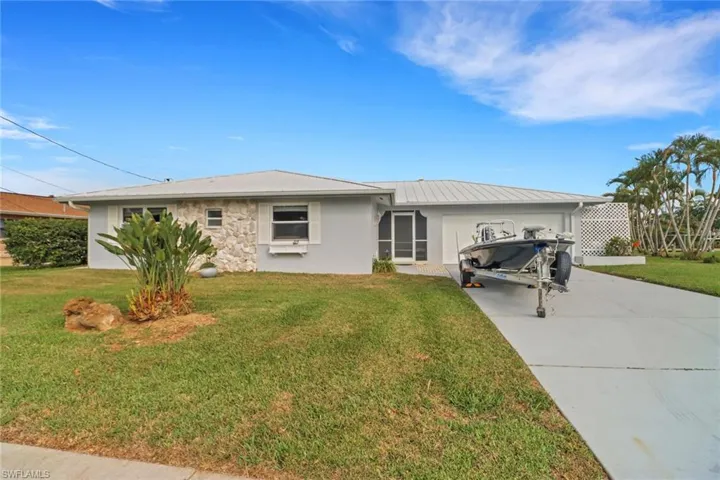 Single story home with a garage and a front lawn