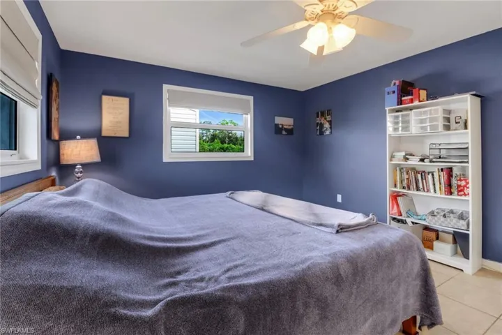 Tiled bedroom featuring ceiling fan