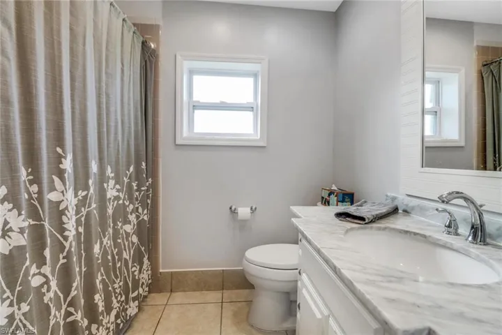 Bathroom with vanity, a shower with curtain, tile patterned floors, and toilet