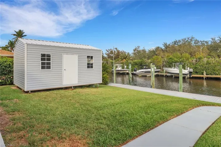 View of outbuilding with a water view and a lawn