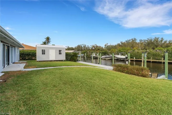 View of yard with a water view, a shed, and a boat dock