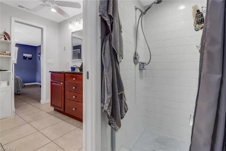 Bathroom featuring vanity, tile patterned floors, ceiling fan, and walk in shower