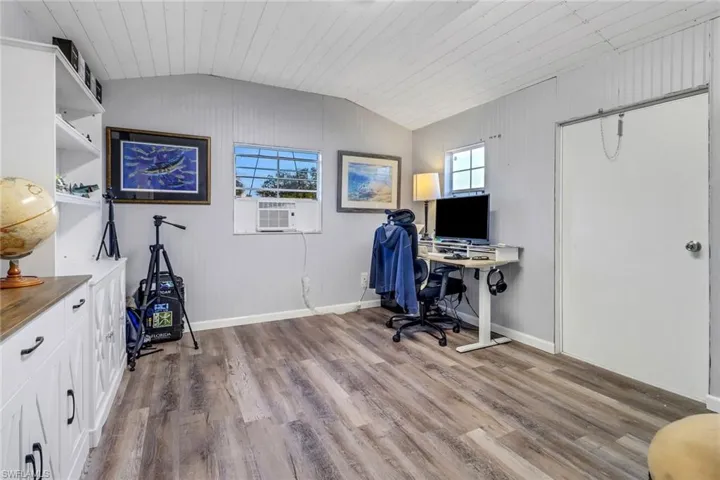 Home office featuring lofted ceiling, cooling unit, light hardwood / wood-style flooring, and wooden ceiling