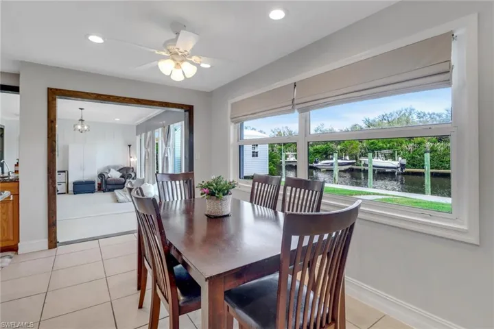 Dining area with ceiling fan with notable chandelier, a water view, sink, and light tile patterned floors