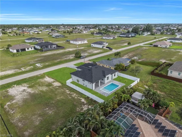 Contemporary-style residence featuring a dark shingle roof, white privacy fence, and a rectangular swimming pool