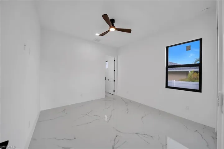 Expansive flooring with a marble-effect finish, complemented by a contemporary ceiling fan with integrated lighting