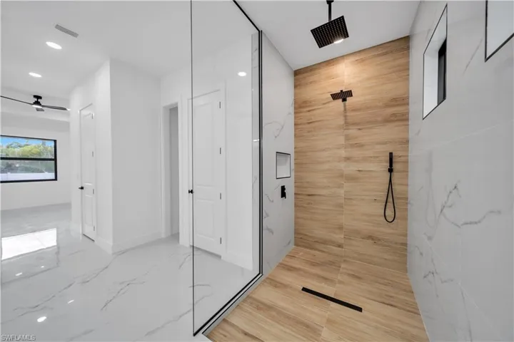 Glass-enclosed shower with wood-finish tile and matte black fixtures