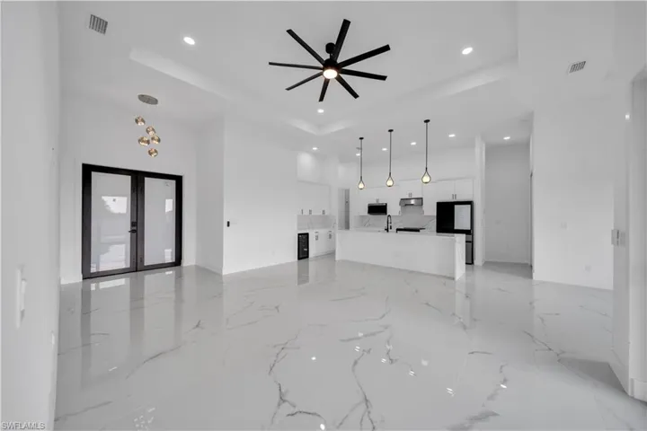 Spacious open-concept interior featuring large format tile flooring, a tray ceiling, and recessed lighting