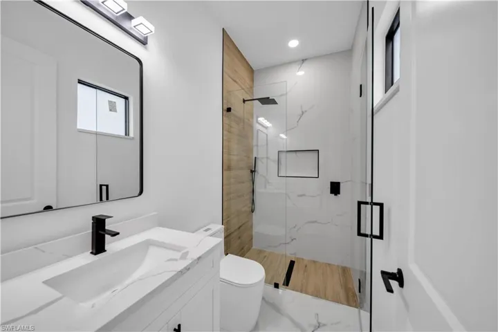 Vanity with integrated sink, black fixtures, and framed mirror