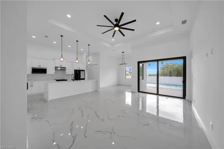 White shaker cabinetry with dark hardware, a tile backsplash, and an eat-at island