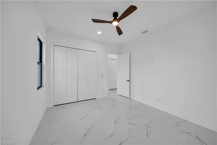 Recessed ceiling lighting, a contemporary ceiling fan, and white paneled bi-fold closet doors
