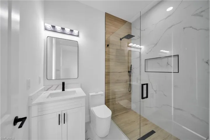 Walk-in shower with clear glass enclosure and wood-finish wall tile