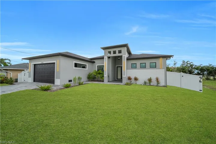 Modern stucco exterior with dark trim and a prominent two-car garage