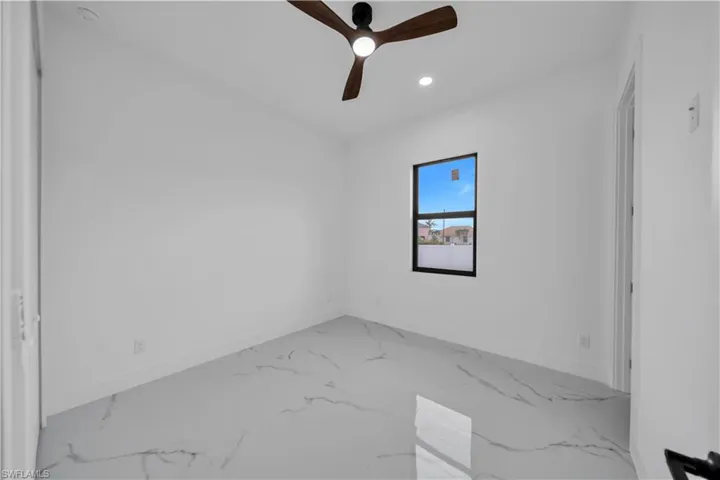 Wood-finish ceiling fan, recessed lighting, single window with black trim, and large format tile flooring
