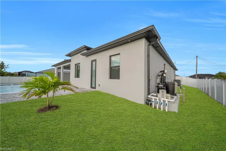 Modern stucco exterior with dark-framed windows, a covered patio, and a swimming pool with paver decking