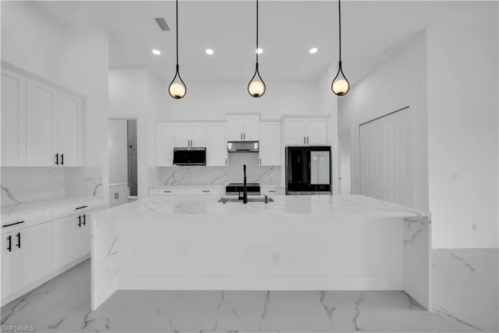 Expansive kitchen island with waterfall edge, integrated sink, and matte black faucet