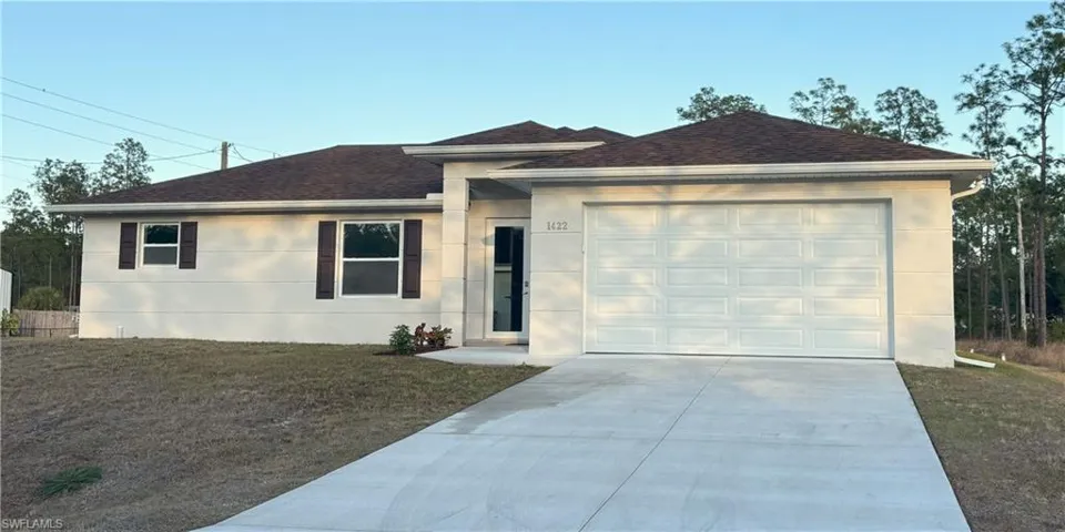 Ranch-style house with concrete driveway, roof with shingles, an attached garage, a front yard, and stucco siding