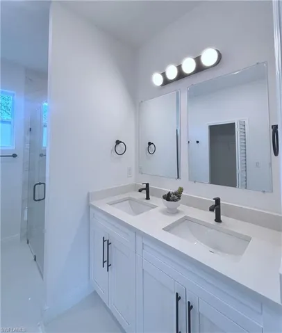 Full bath featuring double vanity and a stall shower