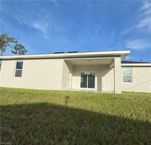 Rear view of property featuring stucco siding and a lawn