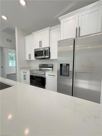 Kitchen with appliances with stainless steel finishes, light countertops, white cabinets, and recessed lighting