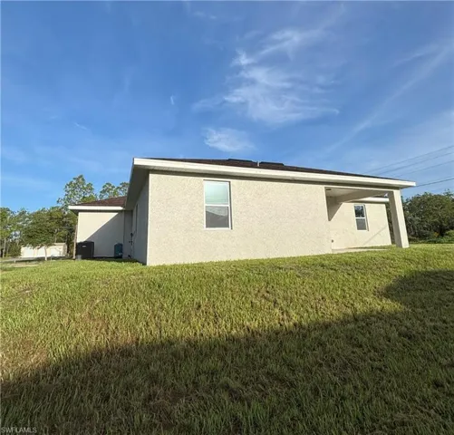 View of property exterior featuring stucco siding and a yard