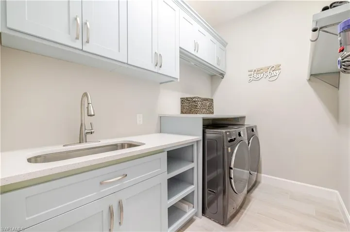 Washroom with light wood-style floors, cabinet space, and washing machine and clothes dryer