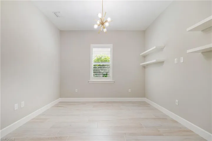 Spare room featuring a chandelier and wood finish floors