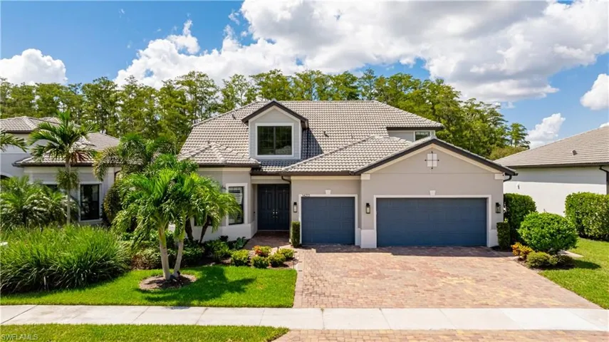 View of front of house featuring a tiled roof, stucco siding, decorative driveway, and a garage
