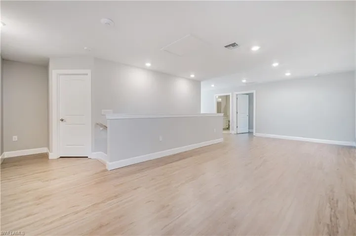 Unfurnished room featuring light wood-style floors, recessed lighting, and attic access