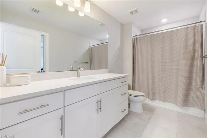 Bathroom featuring shower / tub combo, vanity, and light tile patterned flooring