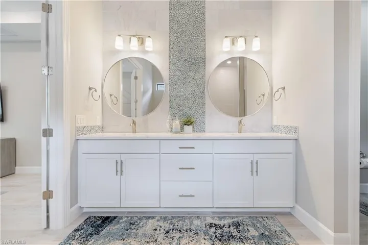 Bathroom featuring double vanity, light wood-type flooring, and tasteful backsplash