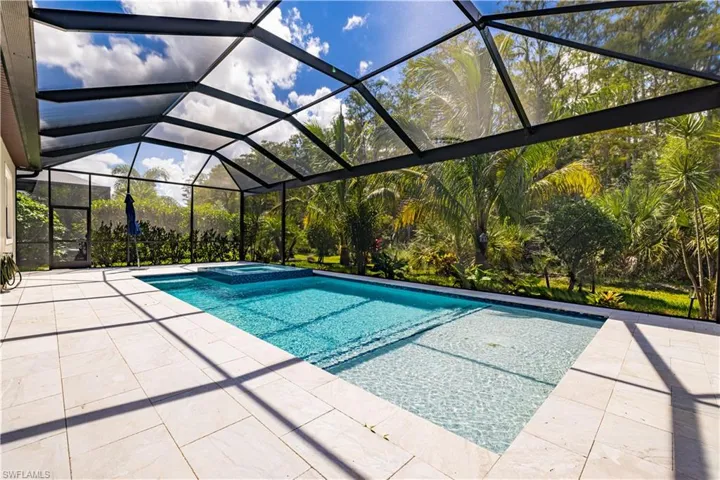 View of pool featuring a pool with connected hot tub, a sunroom, glass enclosure, and a patio