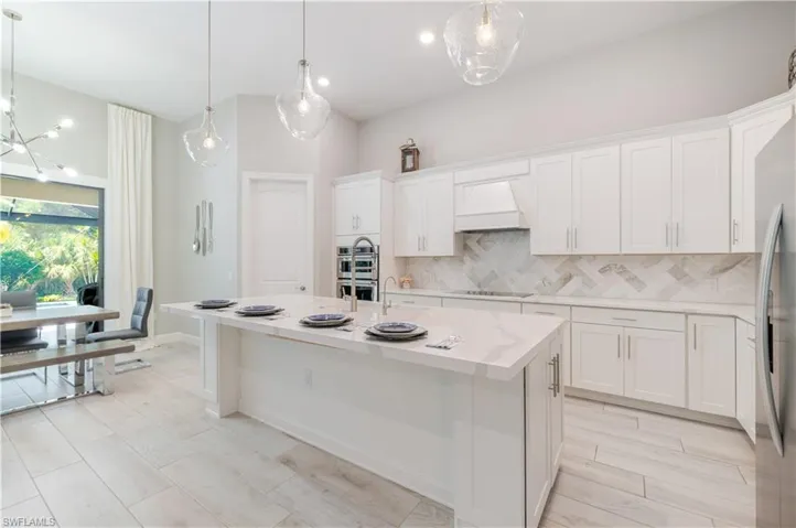 Kitchen with white cabinets, light stone counters, decorative light fixtures, tasteful backsplash, and recessed lighting