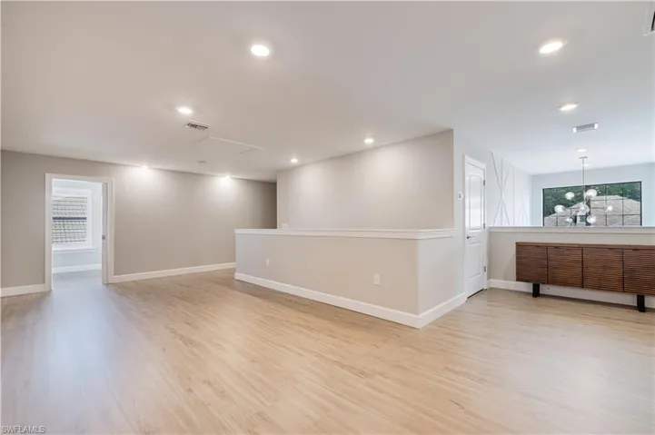 Unfurnished room featuring plenty of natural light, light wood finished floors, recessed lighting, and attic access