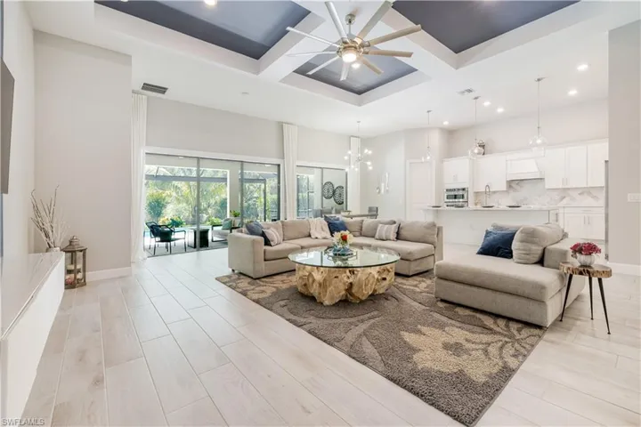 Living area with coffered ceiling, a chandelier, beamed ceiling, recessed lighting, and a towering ceiling