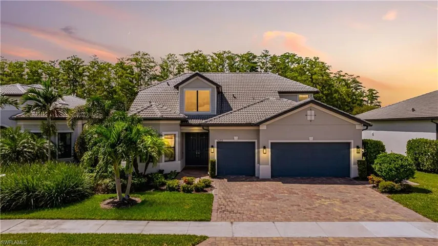 View of front of property with a tile roof, stucco siding, decorative driveway, a garage, and a front lawn